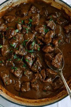 a pot filled with meat and gravy on top of a white table cloth