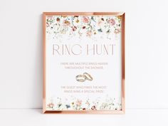 a wedding sign with two rings on it and flowers in the background that says ring hunt