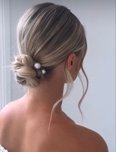 a woman with her hair in a low bun and two pearls on the back of her head