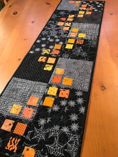 the table runner is decorated with black and orange quilts, spider webs, and stars