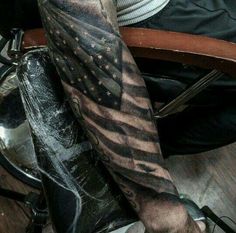 a man's arm with an american flag tattoo on it, sitting in a chair