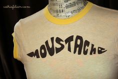 a yellow and white shirt with the word moustache written in black on it