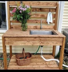 an outdoor sink made out of pallets and wooden planks with a hose attached to it