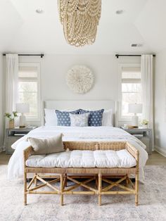 a bedroom with a bed, bench and chandelier hanging from it's ceiling