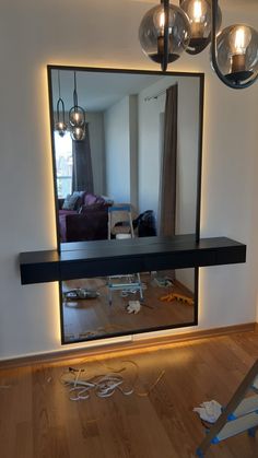 a large mirror sitting on top of a wooden floor in front of a light fixture