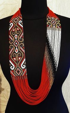 a black mannequin with red and white beaded necklaces on it's neck