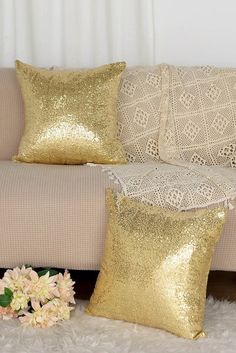 gold sequin pillows on a couch with white furnishing and flowers in the foreground