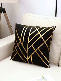 a black and gold pillow sitting on top of a white couch next to a lamp