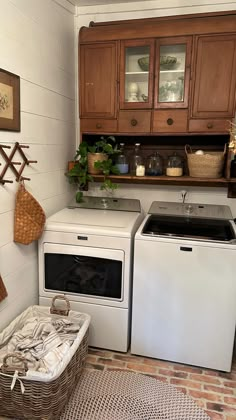 a washer and dryer sitting in a kitchen next to each other with baskets on the floor