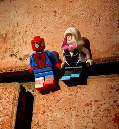 two lego spider - man figures sitting on top of a brick wall next to each other