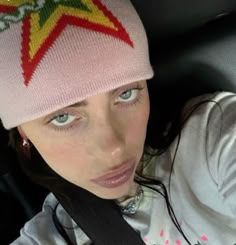 a young woman wearing a pink hat while sitting in a car