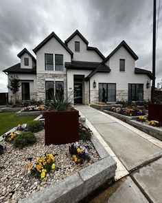 a large white house with lots of flowers in the front yard