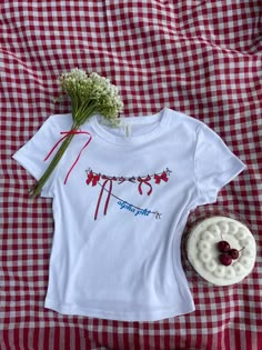 a white t - shirt sitting on top of a red and white checkered table cloth