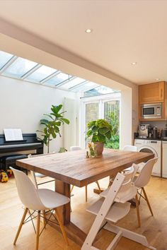 a dining room table with chairs and a potted plant on top of it in front of a piano