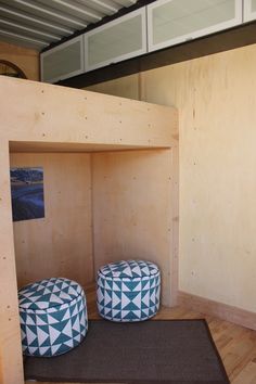 two blue and white poufles sit on the floor in front of a wooden wall