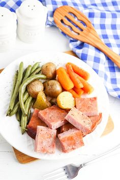 a white plate topped with meat, potatoes and green beans next to a spatula