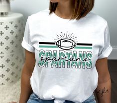 a woman wearing a white t - shirt with the words spartans and a football on it