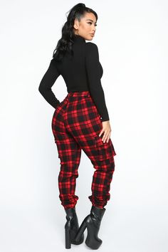 a woman in black top and red plaid pants with high heels on her feet, posing for