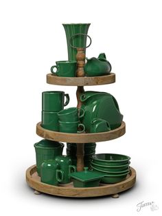 three tiered tray with green dishes and cups stacked on top of each other in front of a white background