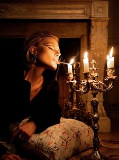 a woman sitting in front of a candelabra with candles