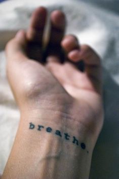 a person's arm with the word breathe tattooed on it, in black ink