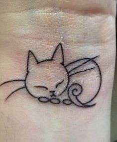 a small tattoo on the wrist of a person with a cat's head and tail