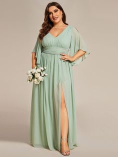 a woman in a long green dress is posing for the camera with her hands on her hips