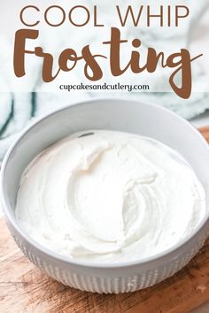 a bowl filled with white frosting on top of a wooden cutting board