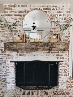 a fireplace with a mirror above it and some pumpkins sitting on top of the mantle