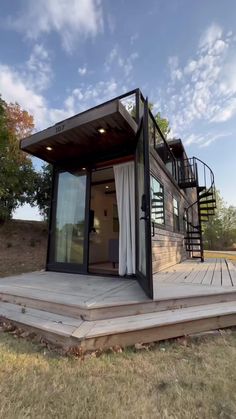 a small house that is sitting in the grass with stairs leading up to it's roof