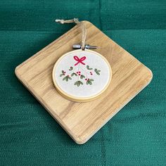 a cross stitch ornament hanging on a wooden board with green fabric behind it