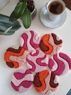 several pieces of knitted coasters sitting on a table next to a cup of coffee