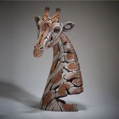 a giraffe statue made out of rocks on a white surface with grey background