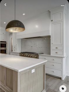 a large kitchen with an island in the middle and two pendant lights hanging from the ceiling