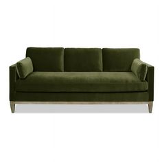 a green velvet couch with wooden legs and pillows on the back, in front of a white background