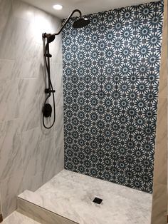 a bathroom with blue and white tile on the shower wall, next to a black faucet