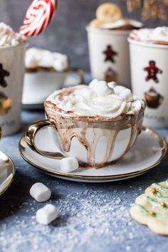 hot chocolate and marshmallows in cups with candy canes on the side