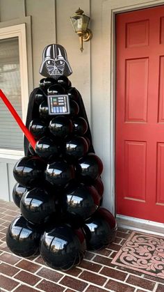 darth vader christmas tree made out of bowling balls is shown in front of a red door