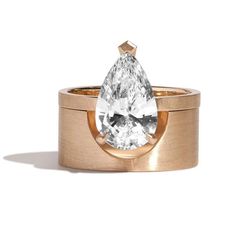 a gold ring with a pear shaped diamond in the center and a thin band around it