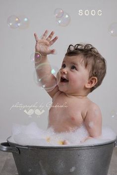 a baby sitting in a bucket with soap bubbles