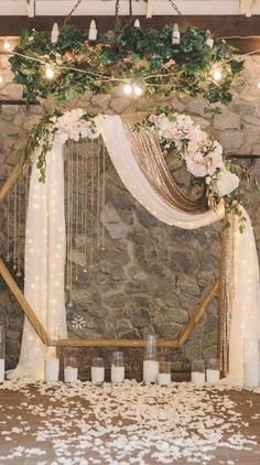 a stone wall with candles and flowers on it is decorated with greenery and lights