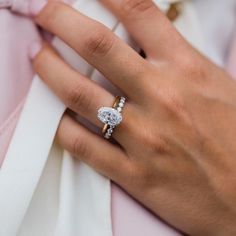 a woman's hand with a diamond ring on her finger and a pink dress