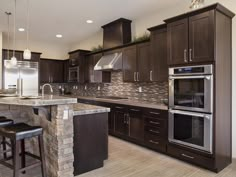 a large kitchen with an island in the middle and two stools at the counter