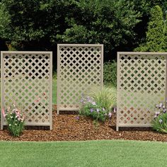 three wooden privacy screens in the middle of a flower bed with purple and white flowers