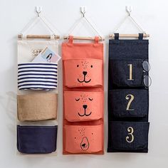 three storage bags hanging on a wall with numbers and animals drawn on the side,