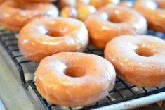 several glazed donuts are cooling on a rack