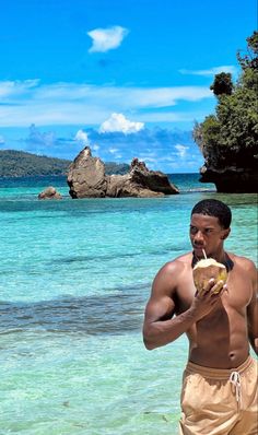 a man standing on the beach holding a piece of food in his hand and looking at the camera