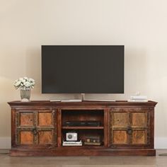 an entertainment center with a flat screen tv mounted on it's side, in front of a white wall