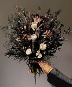 a bouquet of flowers is being held by someone's hand with long black gloves