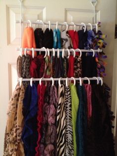 there is a rack full of scarves hanging on the door handle and some hangers